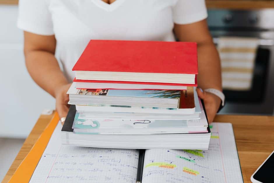 Auteure tenant une pile de ses livres imprimés au-dessus de son carnet de travail